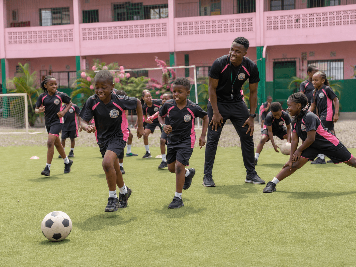 A Calvary sports coach guiding students through football practice on the school field